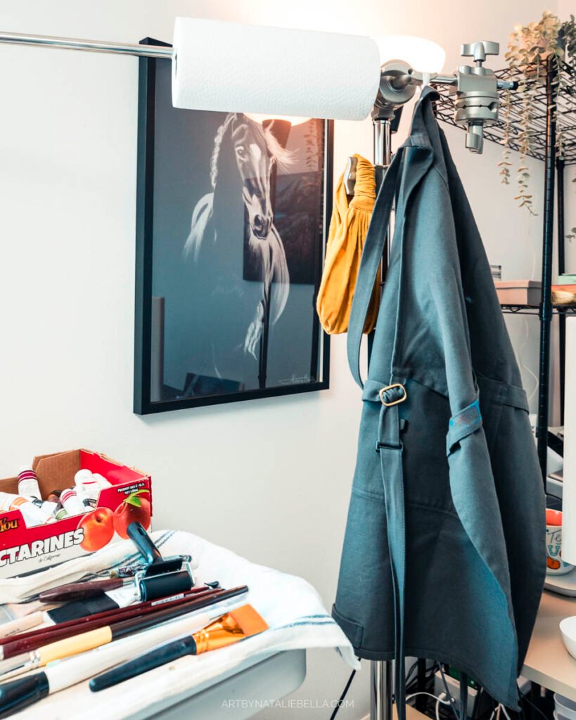 Contemporary art studio interior with a C-stand, paintings, and creative workspace showing artist's painting process and materials