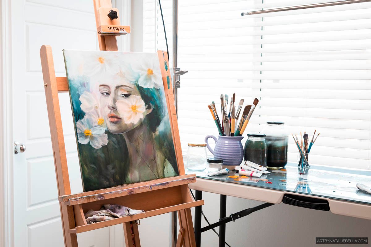 Oil painting of woman with white daisies on wooden easel in bright art studio with paintbrushes, ceramic vessels, and natural window light