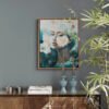 Where Ethereal Dreams Bloom original oil painting by Natalie Bella displayed in modern living room with walnut float frame, featuring ethereal woman portrait with white flowers on gray wall above wooden credenza with blue candlesticks and spider plant