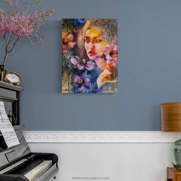 Original mixed media portrait She Chose Light by Natalie Bella displayed on dusty blue wall above white wainscoting in refined living room with piano, pink flowering branches, and antique clock - contemporary feminine art for sophisticated interiors