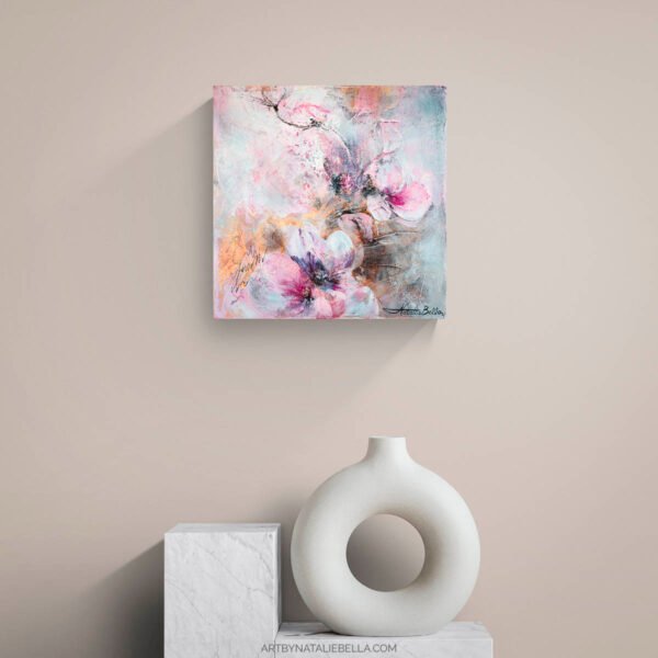 Where Light Lingers - Abstract Floral Art with Gold Leaf Above M Mixed media floral painting with soft pink blossoms and gold leaf accents displayed above white marble pedestals with sculptural ceramic vase in neutral contemporary interior